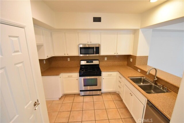 2 Lynde St, Ladera Ranch, CA 92694 - kitchen with appliances with stainless steel finishes, light tile patterned floors, white cabinetry, and a peninsula
