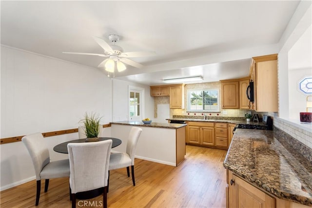 10402 Oronsay Cir, Huntington Beach, CA 92646 - kitchen featuring range with gas stovetop, decorative backsplash, light wood-style floors, and dark stone countertops