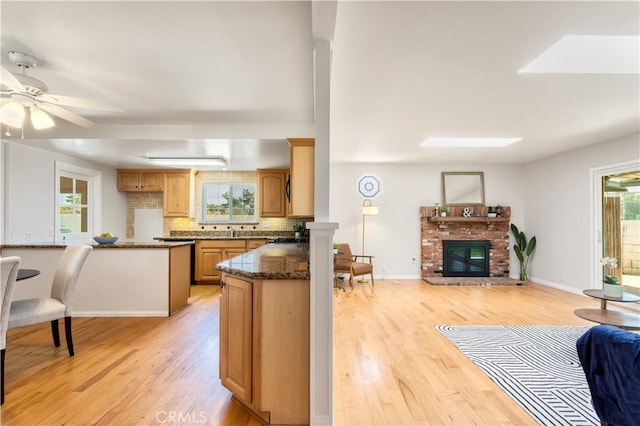 10402 Oronsay Cir, Huntington Beach, CA 92646 - kitchen featuring light wood-type flooring, a ceiling fan, backsplash, open floor plan, and a brick fireplace