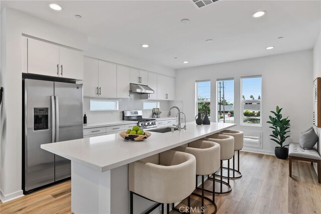 536 Caleigh Ln, Costa Mesa, CA 92627 - kitchen featuring stainless steel appliances, under cabinet range hood, a sink, light countertops, and a kitchen bar