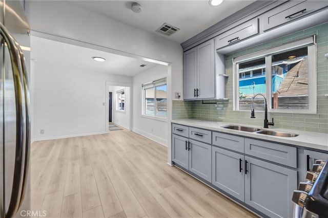 210 Amabel St, Los Angeles, CA 90065 - kitchen with gray cabinetry, stainless steel refrigerator, light countertops, tasteful backsplash, and light wood-style flooring