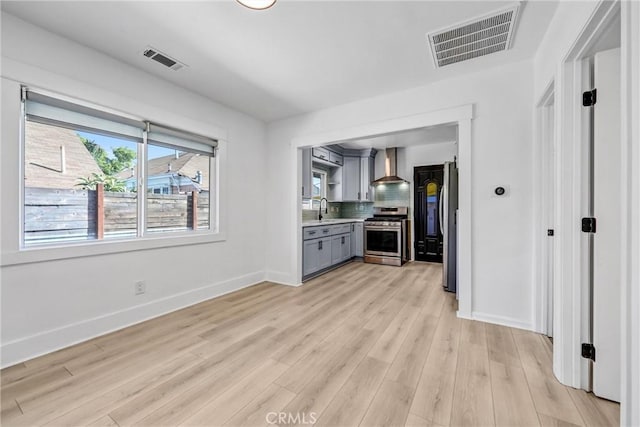 210 Amabel St, Los Angeles, CA 90065 - kitchen with stainless steel stove, wall chimney exhaust hood, gray cabinets, decorative backsplash, and light wood-type flooring