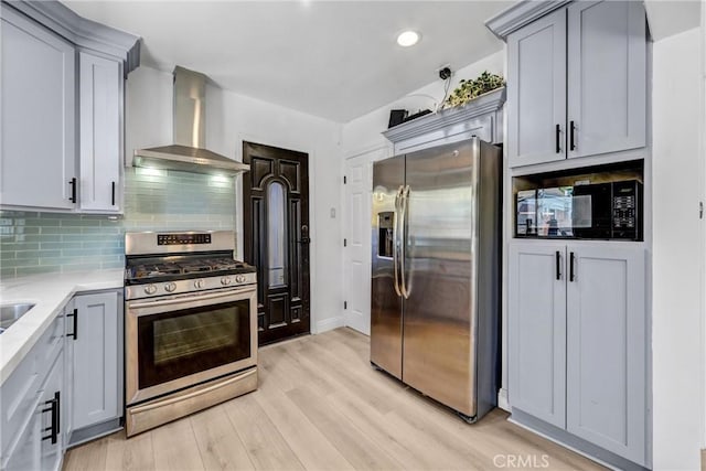 210 Amabel St, Los Angeles, CA 90065 - kitchen featuring appliances with stainless steel finishes, wall chimney exhaust hood, light wood-type flooring, decorative backsplash, and light countertops