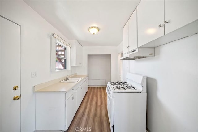 823 W 25th St, San Pedro, CA 90731 - kitchen with white range with gas stovetop, under cabinet range hood, a sink, light countertops, and light wood-style floors