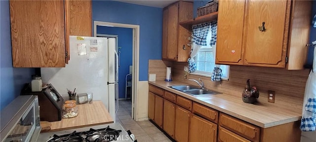 1623 S Sycamore Ave, Los Angeles, CA 90019 - kitchen with stainless steel microwave, light countertops, tasteful backsplash, brown cabinets, and freestanding refrigerator