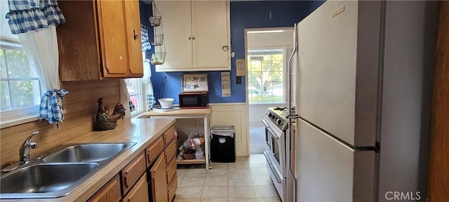 1623 S Sycamore Ave, Los Angeles, CA 90019 - kitchen with freestanding refrigerator, black microwave, gas range, brown cabinets, and light countertops