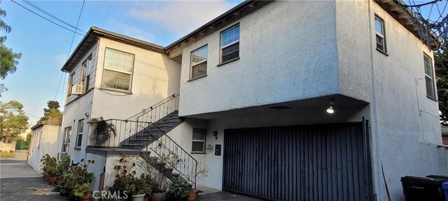 1623 S Sycamore Ave, Los Angeles, CA 90019 - view of side of home with stucco siding, stairs, and an attached garage