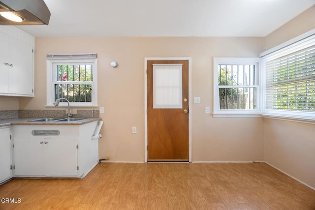  - kitchen featuring light wood finished floors, white cabinets, and light countertops