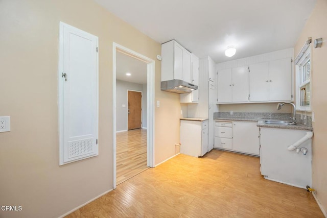  - kitchen featuring light wood-type flooring, white cabinetry, and under cabinet range hood