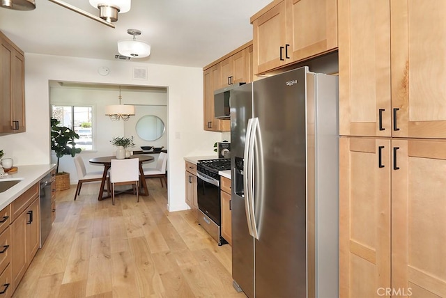 9864 Van Ruiten St, Bellflower, CA 90706 - kitchen with appliances with stainless steel finishes, light wood finished floors, light countertops, light brown cabinetry, and hanging light fixtures
