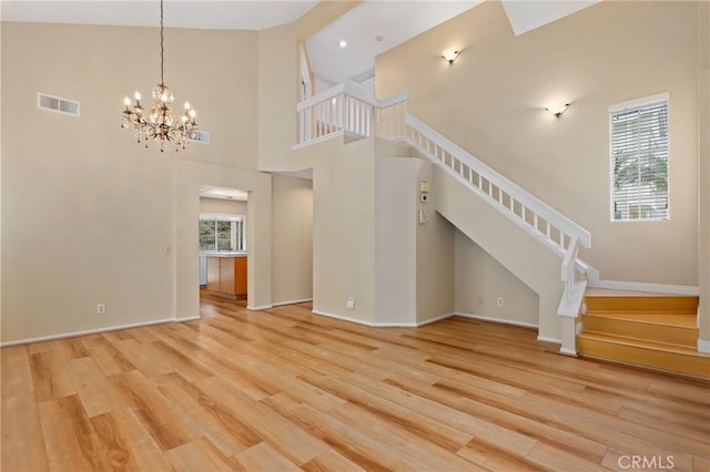 28462 La Alcala, Laguna Niguel, CA 92677 - unfurnished living room with stairs, wood finished floors, a chandelier, and a towering ceiling