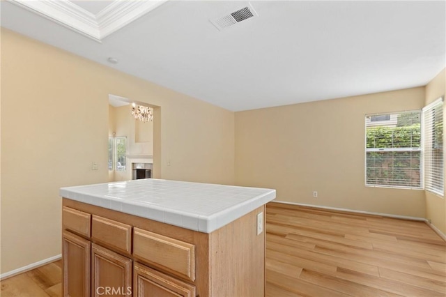 28462 La Alcala, Laguna Niguel, CA 92677 - kitchen featuring light wood-style flooring, tile counters, a chandelier, a fireplace, and ornamental molding