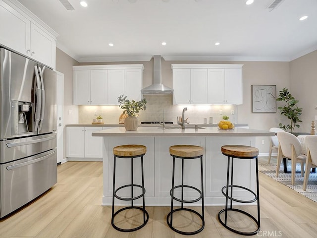 159 Frazier, Irvine, CA 92620 - kitchen featuring stainless steel fridge, wall chimney range hood, light wood finished floors, a breakfast bar, and crown molding