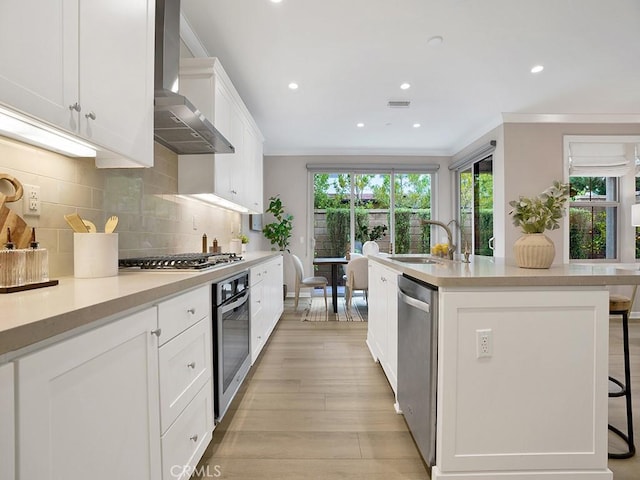 159 Frazier, Irvine, CA 92620 - kitchen featuring appliances with stainless steel finishes, wall chimney range hood, a sink, ornamental molding, and a center island with sink