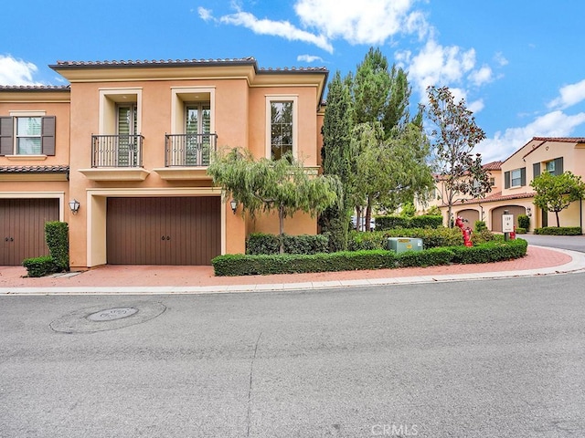 159 Frazier, Irvine, CA 92620 - view of front of house featuring a tile roof, a balcony, stucco siding, a garage, and driveway
