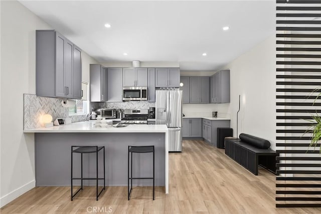 2129 N Pepper St, Burbank, CA 91505 - kitchen featuring appliances with stainless steel finishes, gray cabinetry, a peninsula, decorative backsplash, and light wood finished floors