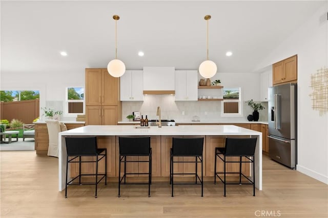 2796 Cibola Ave, Costa Mesa, CA 92626 - kitchen with high end fridge, decorative backsplash, light countertops, light wood-style flooring, and a spacious island