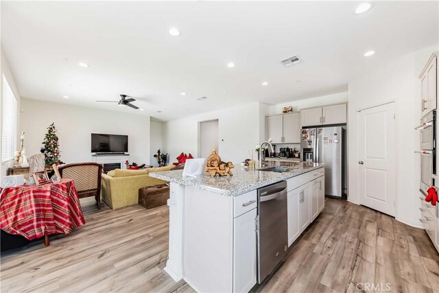 29485 Whitewood St, Menifee, CA 92584 - kitchen featuring appliances with stainless steel finishes, recessed lighting, light wood-style floors, light stone countertops, and a center island with sink