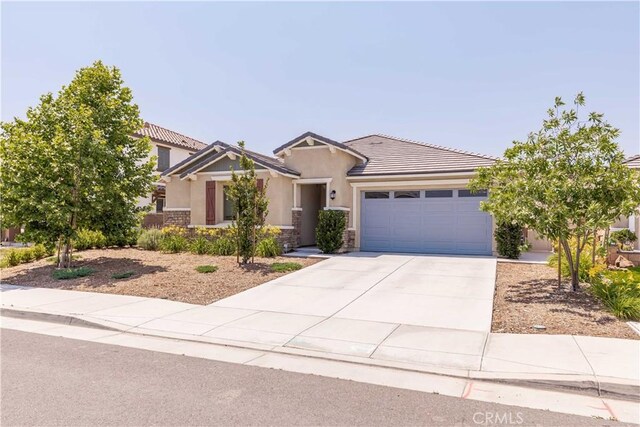 29485 Whitewood St, Menifee, CA 92584 - view of front of house featuring a garage, driveway, stone siding, stucco siding, and a tiled roof