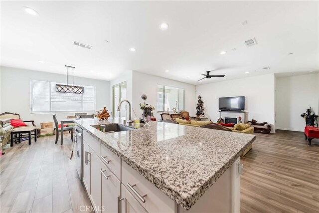 29485 Whitewood St, Menifee, CA 92584 - kitchen featuring light wood-style flooring, a center island with sink, recessed lighting, a ceiling fan, and light stone counters