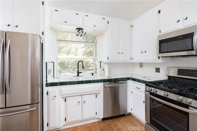 1268 Aleutian Dr, Lake Arrowhead, CA 92352 - kitchen featuring appliances with stainless steel finishes, a sink, tile countertops, and white cabinets