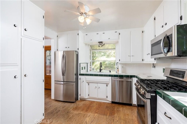 1268 Aleutian Dr, Lake Arrowhead, CA 92352 - kitchen featuring stainless steel appliances, tile countertops, a sink, and white cabinets