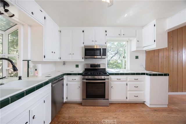 1268 Aleutian Dr, Lake Arrowhead, CA 92352 - kitchen featuring stainless steel appliances, tile countertops, white cabinetry, and wood walls