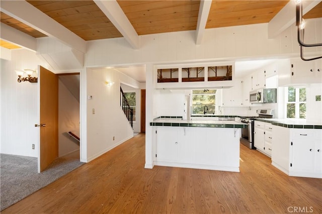 1268 Aleutian Dr, Lake Arrowhead, CA 92352 - kitchen featuring stainless steel appliances, tile counters, white cabinetry, a sink, and wooden ceiling with exposed beams