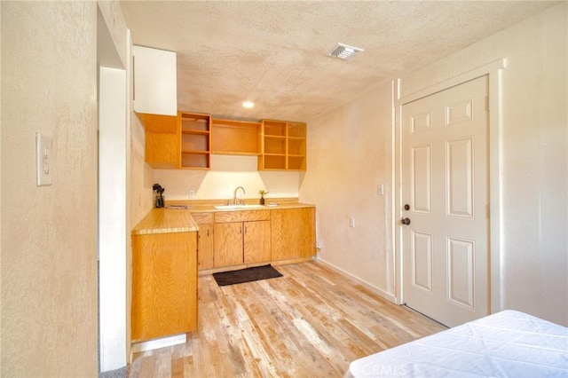 1131 Apple Ave, Wrightwood, CA 92397 - kitchen with open shelves, a sink, light wood-style floors, light countertops, and a textured ceiling