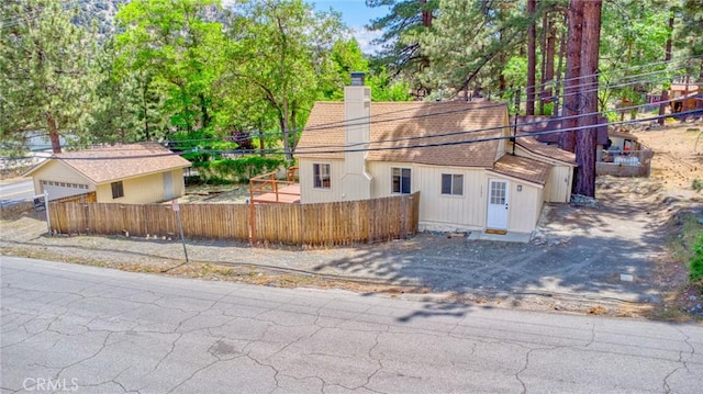 1131 Apple Ave, Wrightwood, CA 92397 - view of side of home with a fenced front yard, a chimney, a garage, and a shingled roof