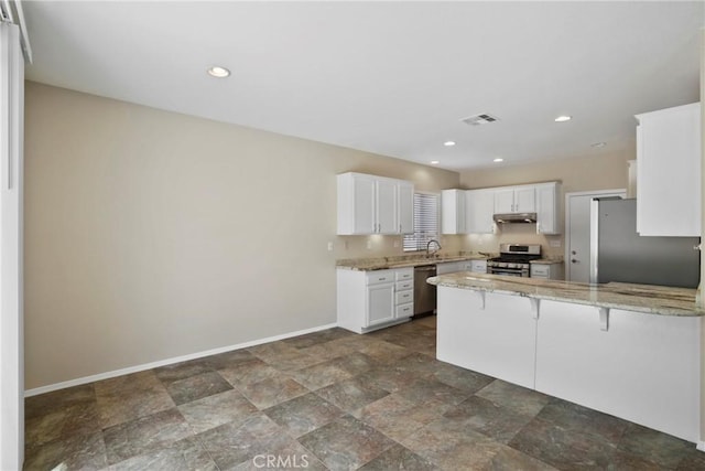 31713 Pompei Ln, Winchester, CA 92596 - kitchen with appliances with stainless steel finishes, under cabinet range hood, a peninsula, white cabinetry, and light stone countertops