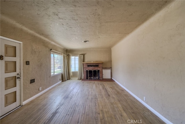 503 California Ave, Needles, CA 92363 - unfurnished living room featuring a fireplace, hardwood / wood-style floors, and baseboards