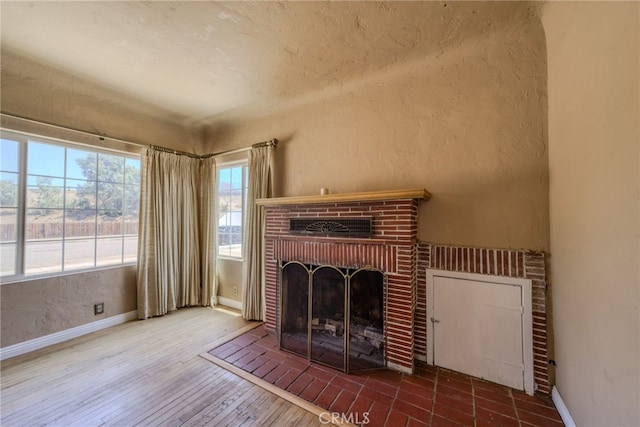 503 California Ave, Needles, CA 92363 - unfurnished living room with baseboards, a fireplace, wood finished floors, and a textured wall