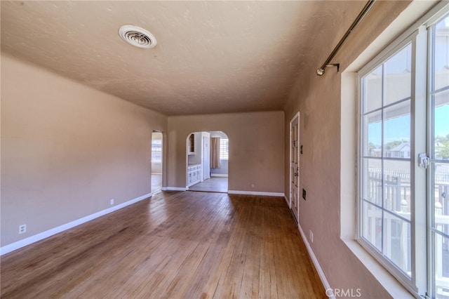 503 California Ave, Needles, CA 92363 - spare room featuring arched walkways, baseboards, and wood-type flooring