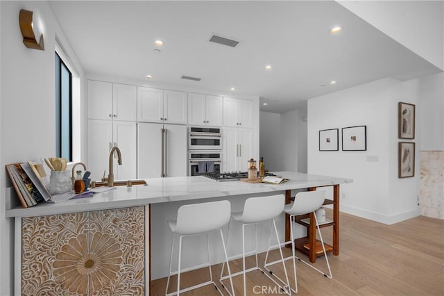 2004 Grant Ave Unit B, Redondo Beach, CA 90278 - kitchen featuring double oven, light wood-type flooring, white cabinetry, light stone counters, and recessed lighting