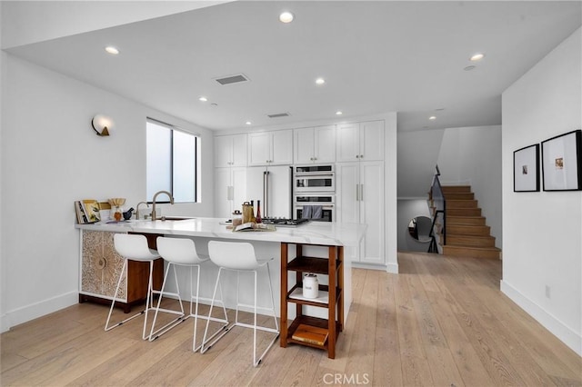 2004 Grant Ave Unit B, Redondo Beach, CA 90278 - kitchen featuring double oven, a peninsula, white cabinets, light wood-type flooring, and light countertops