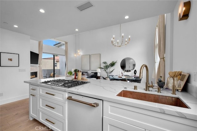 2004 Grant Ave Unit B, Redondo Beach, CA 90278 - kitchen with light stone countertops, white cabinets, a chandelier, stainless steel gas stovetop, and light wood-type flooring