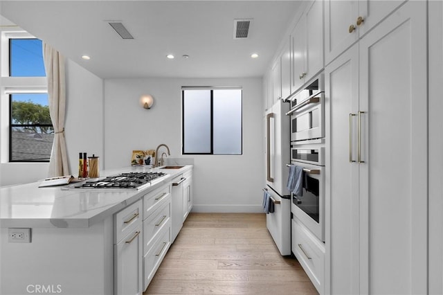 2004 Grant Ave Unit B, Redondo Beach, CA 90278 - kitchen with appliances with stainless steel finishes, light wood-style flooring, white cabinetry, recessed lighting, and a peninsula