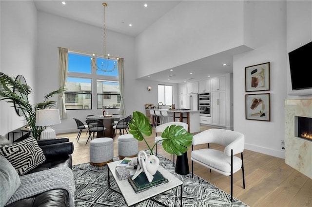 2004 Grant Ave Unit B, Redondo Beach, CA 90278 - living room featuring a high ceiling, light wood-type flooring, a premium fireplace, a chandelier, and recessed lighting