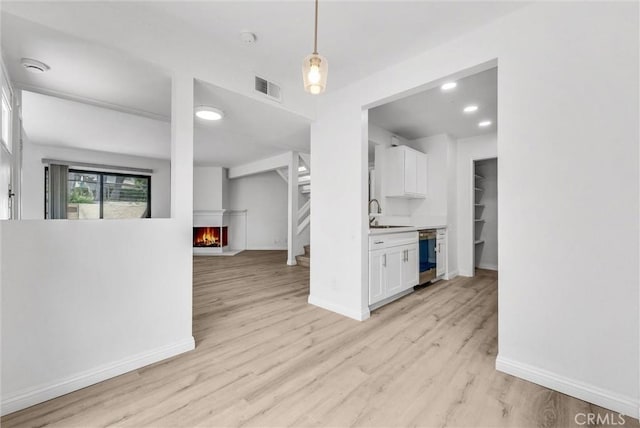 13104 Glen Ct Unit 28, Chino Hills, CA 91709 - kitchen featuring white cabinets, a lit fireplace, light wood-style floors, light countertops, and pendant lighting