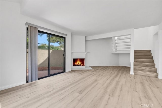 13104 Glen Ct Unit 28, Chino Hills, CA 91709 - unfurnished living room with wood finished floors, stairs, and a warm lit fireplace