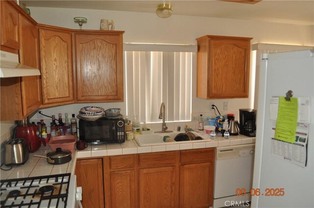 11584 Oak St, Apple Valley, CA 92308 - kitchen featuring white appliances, a sink, under cabinet range hood, tile counters, and brown cabinets