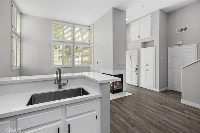 8308 Atlanta Ave Unit 101, Huntington Beach, CA 92646 - kitchen featuring a sink, white cabinets, dark wood-type flooring, baseboards, and a fireplace
