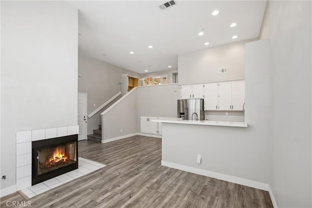 8308 Atlanta Ave Unit 101, Huntington Beach, CA 92646 - unfurnished living room with baseboards, recessed lighting, wood finished floors, a tiled fireplace, and stairway