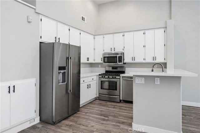 8308 Atlanta Ave Unit 101, Huntington Beach, CA 92646 - kitchen with appliances with stainless steel finishes, dark wood-style flooring, light countertops, a peninsula, and a towering ceiling
