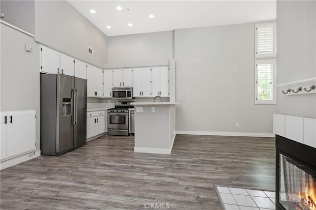 8308 Atlanta Ave Unit 101, Huntington Beach, CA 92646 - kitchen featuring stainless steel appliances, open floor plan, baseboards, wood finished floors, and a high ceiling