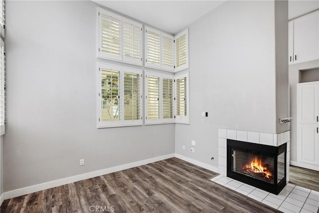 8308 Atlanta Ave Unit 101, Huntington Beach, CA 92646 - unfurnished living room with a tile fireplace, dark wood-style floors, baseboards, and a towering ceiling