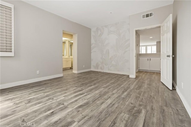 8308 Atlanta Ave Unit 101, Huntington Beach, CA 92646 - unfurnished room featuring wallpapered walls, wood finished floors, baseboards, and an accent wall