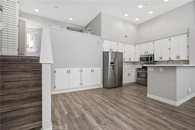 8308 Atlanta Ave Unit 101, Huntington Beach, CA 92646 - kitchen with appliances with stainless steel finishes, dark wood-type flooring, white cabinets, recessed lighting, and a towering ceiling