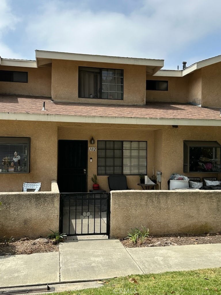 1034 E 6th St Unit 102, Ontario, CA 91764 - view of front of home with a fenced front yard, stucco siding, a gate, and a porch
